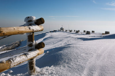 Snow covered wooden posts on land against sky