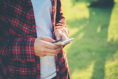 Midsection of woman using phone on field