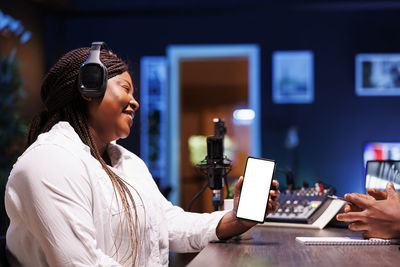 Side view of young woman using mobile phone while standing in office