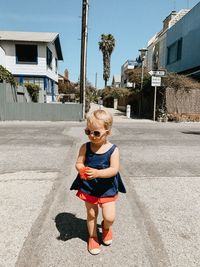 Full length of cute girl wearing sunglasses walking on road