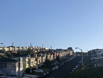 Street amidst buildings against clear blue sky