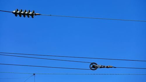 Low angle view of power lines against clear blue sky