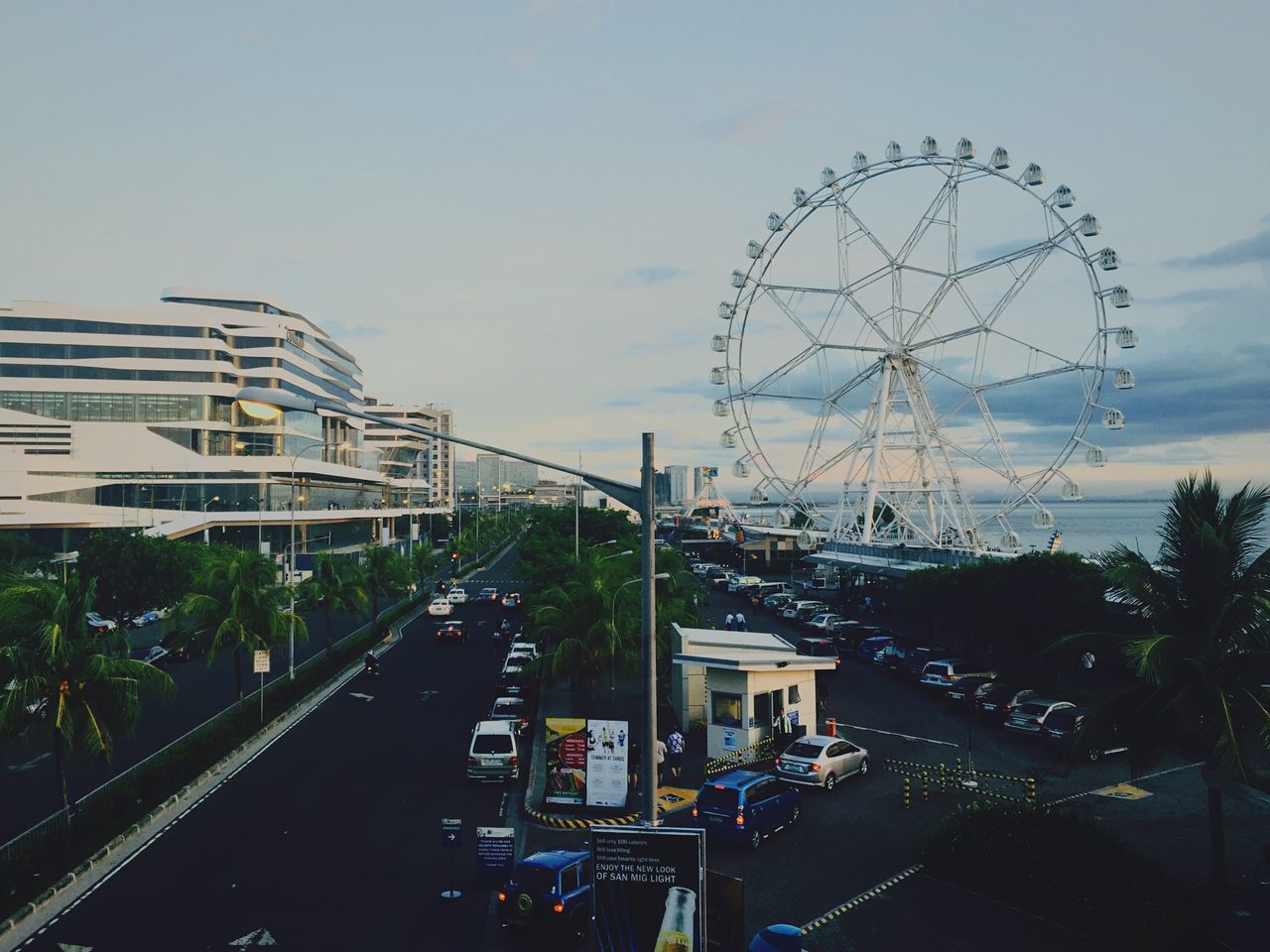 transportation, land vehicle, street, building exterior, built structure, road, architecture, city, mode of transport, sky, car, clear sky, street light, city street, tree, power line, incidental people, outdoors, city life, electricity pylon