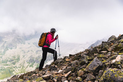 Woman traveler goes to the top of the mountain. a girl with trekking poles and a backpack stopped to