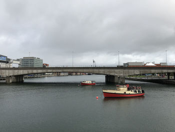 Bridge over river against sky in city