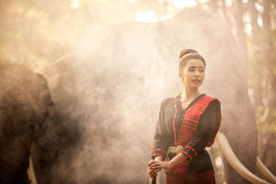 Young woman standing in illuminated fog