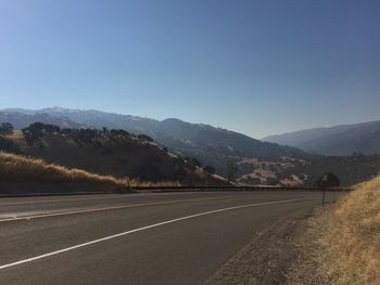 Road by mountains against clear sky