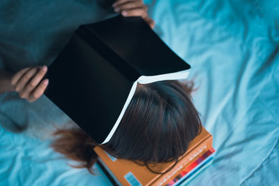  young women lie down on pile of book and cover her face by the book education and growth concept