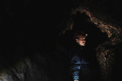 Portrait of young man looking away while standing on rock