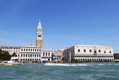Boats at grand canal by san marco campanile tower against clear blue sky