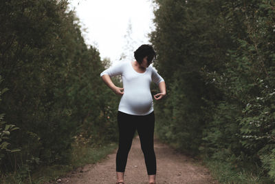 Pregnant woman standing on field amidst plants