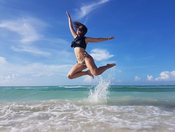 Woman jumping in sea against sky