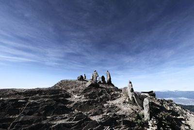People on rock against sky