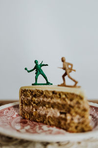Two toy soldiers fighting on the top of a piece of cake about calories - close up - white background