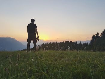 Rear view of silhouette man standing on field against sky