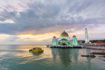 View of church at waterfront against cloudy sky