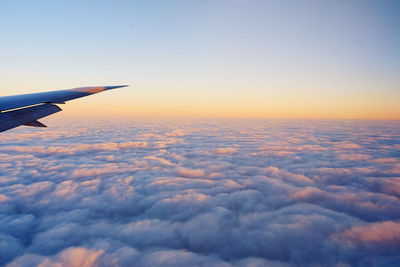 Cropped image of airplane flying above cloudscape at sunset