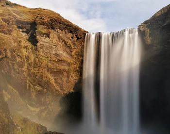 Scenic view of waterfall against sky