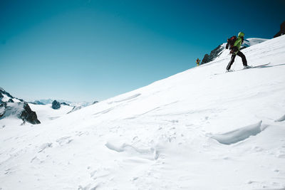 Person on snow covered mountain against clear blue sky