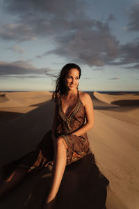 Beautiful young woman on beach against sky