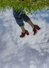 Low section of woman standing on plant against sky