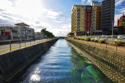 Canal amidst buildings in city against sky