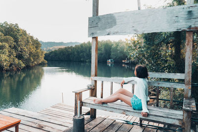 Girl looking at lake against trees