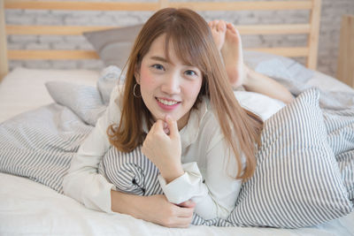 Portrait of a smiling young woman lying on bed