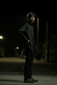 Full length of boy looking at illuminated city at night