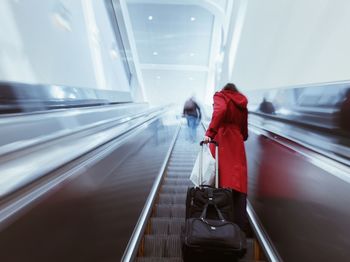 Rear view of woman walking on escalator