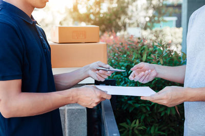 Midsection of delivery person giving customer document to sign 