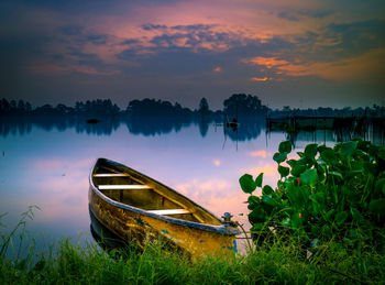 Boat moored in lake against sky during sunset
