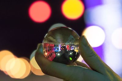 Close-up of hand holding illuminated lighting equipment against sky