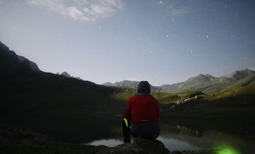 Rear view of man looking at mountain against sky