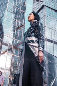 Low angle view of woman looking at buildings in city