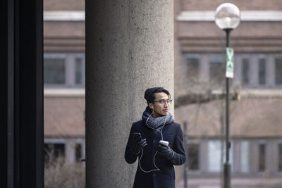 Handsome man with smartphone and paper cup on street