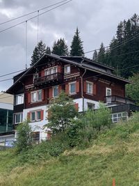 House and trees on field against sky