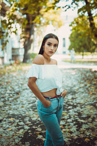 Portrait of young woman standing against trees