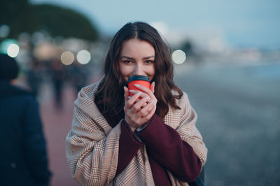 Portrait of beautiful woman standing against blurred background