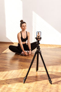 Full length of woman sitting on wooden wall