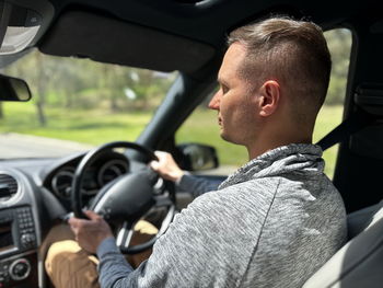 Side view of man driving car