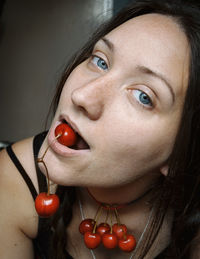 Close-up portrait of young woman eating cherry