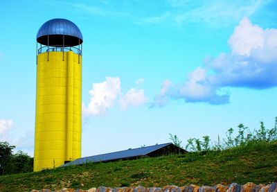 Low angle view of barn and yellow silo against sky