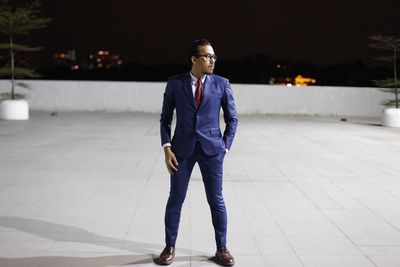 Full length of businessman standing on paved footpath at night