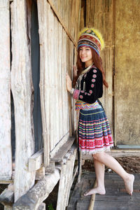 Portrait of smiling girl standing against wooden wall