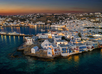 High angle view of townscape by sea during sunset