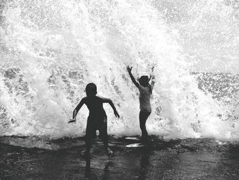Children playing under splashing wave