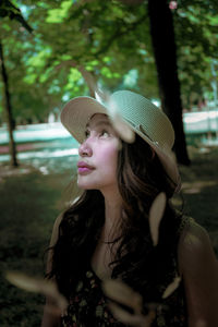 Close-up of mature woman wearing hat looking up sitting outdoors