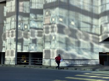 Man walking on street against building in city