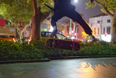 Low section of person skateboarding in city at night